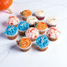 12 mini Halloween Cupcakes decorated as monsters, pumpkins, mummies and brains, next to a pumpkin