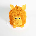 Furby Cake with bright orange spiky buttercream fur, fondant ears, eyes, beak and feet