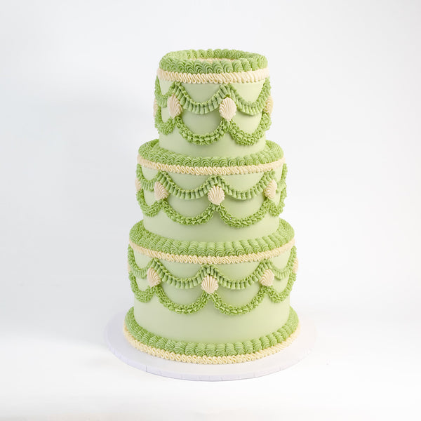 Three-tiered Frilly Wedding Cake with pale green icing, piped ruffles, and scalloped swags, showcasing Harry Batten's creative handmade design.