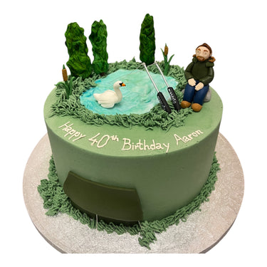 Custom 40th birthday cake with a fondant pond scene, a man fishing, a swan and bulrushes