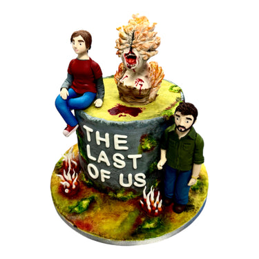 Custom Cake (please contact us before purchasing) featuring “The Last of Us” theme with fondant figures of Joel, Ellie, and a Clicker on mossy terrain.