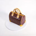 Handbag Cake with a monogram print, gold details and handles, on a cake board