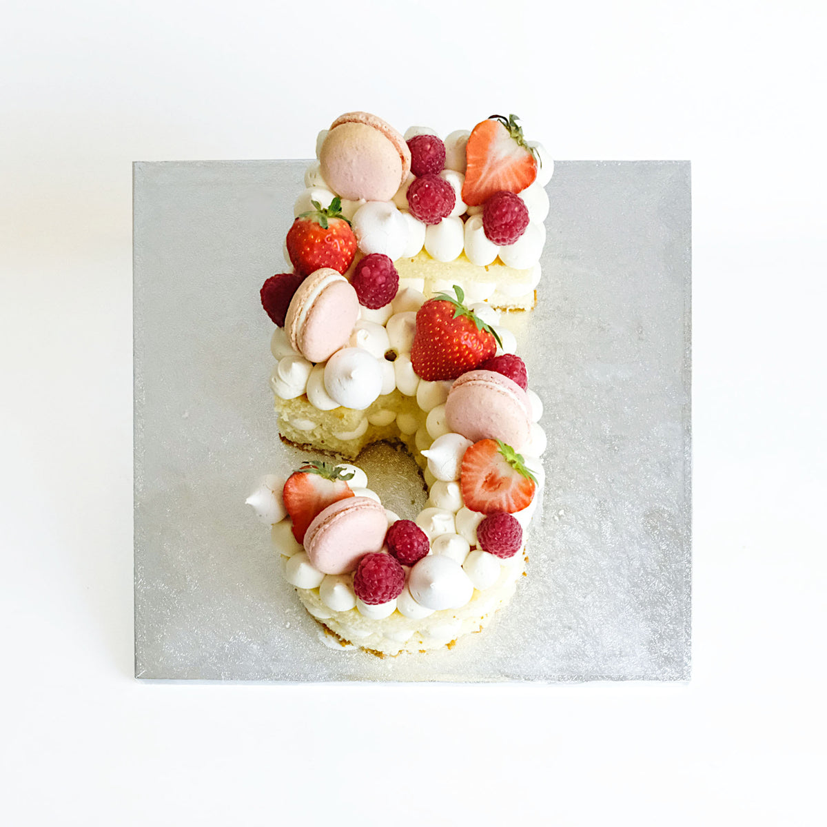 Number Cake with vanilla cream, pink macarons, meringue kisses, strawberries and raspberries