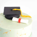 Graduation Cake with pale green buttercream, gold splatters, a fondant graduation cap and scroll
