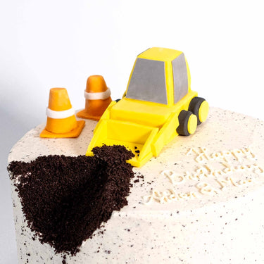 Digger Cake with a yellow fondant digger, chocolate crumb dirt, traffic cones and a happy birthday message