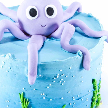 Under The Sea Cake with blue buttercream, fondant seaweed, sprinkles and a purple octopus on top