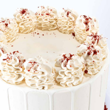 Red Velvet Cake topped with large cream cheese buttercream swirls and a ring of red velvet crumbs