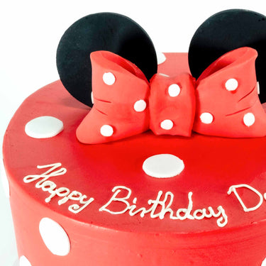 Red Minnie Mouse Cake with white polka dots, a fondant bow and ears, and happy birthday piped on the side