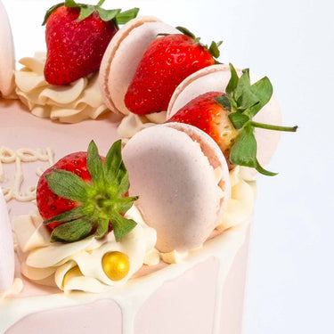 8 inch Strawberry Macaroon Cake with pale pink buttercream, white drip, strawberries, macarons and buttercream rosettes
