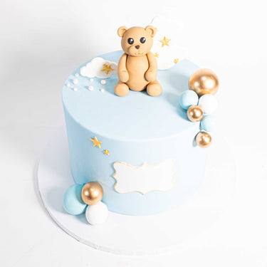 Pale blue Teddy Bear Cake with a fondant bear, clouds, stars and a plaque for a message