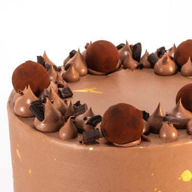 Close up of the Triple Chocolate Cake topped with chocolate truffles, buttercream and chocolate pieces