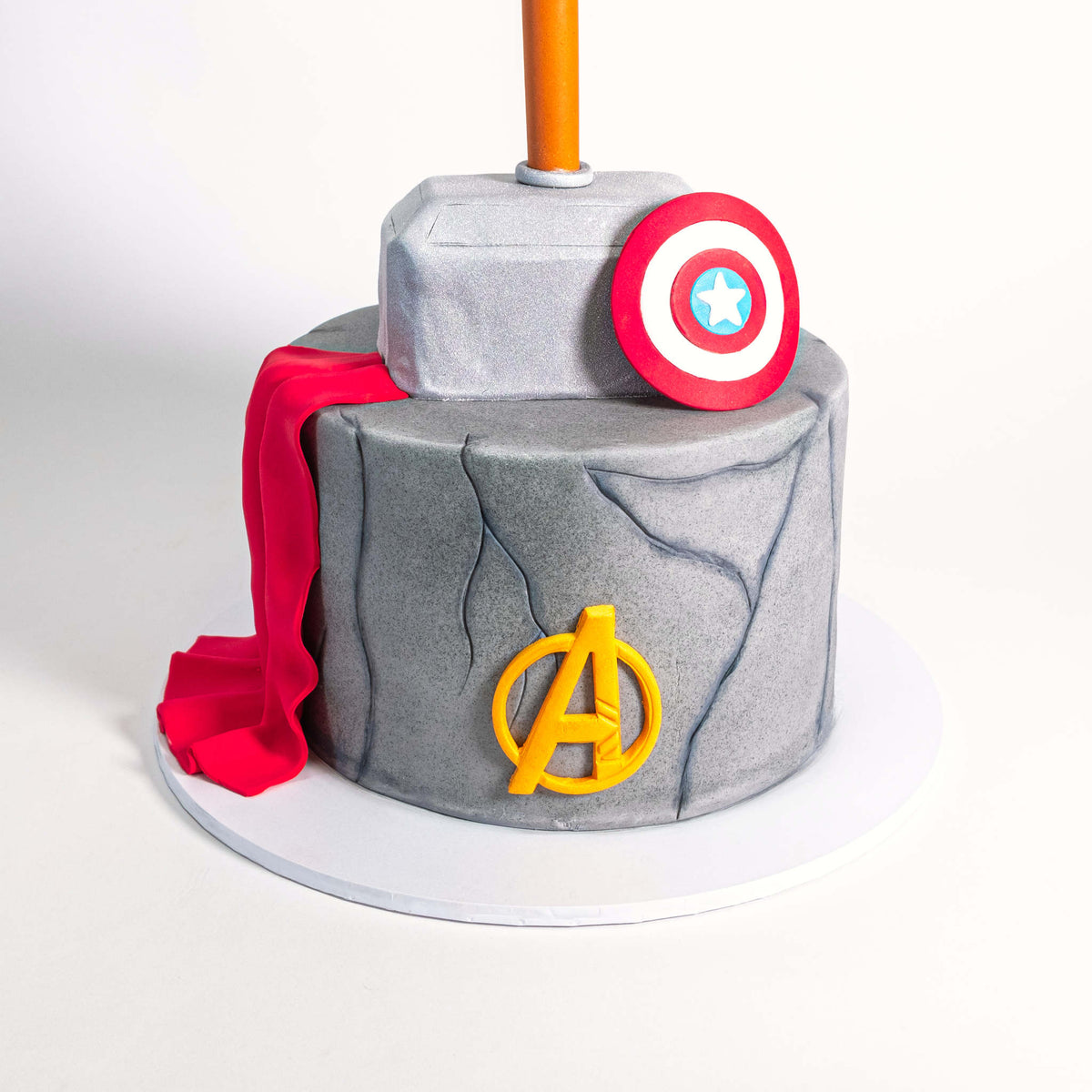 Marvel Avengers Cake with a fondant Thor's hammer, Captain America's shield, Avengers logo and red cape