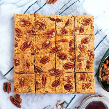 Maple Pecan Blondies topped with pecans, next to extra pecans