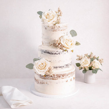 Three tier Naked Wedding Cake with a semi naked buttercream finish, ivory roses and eucalyptus