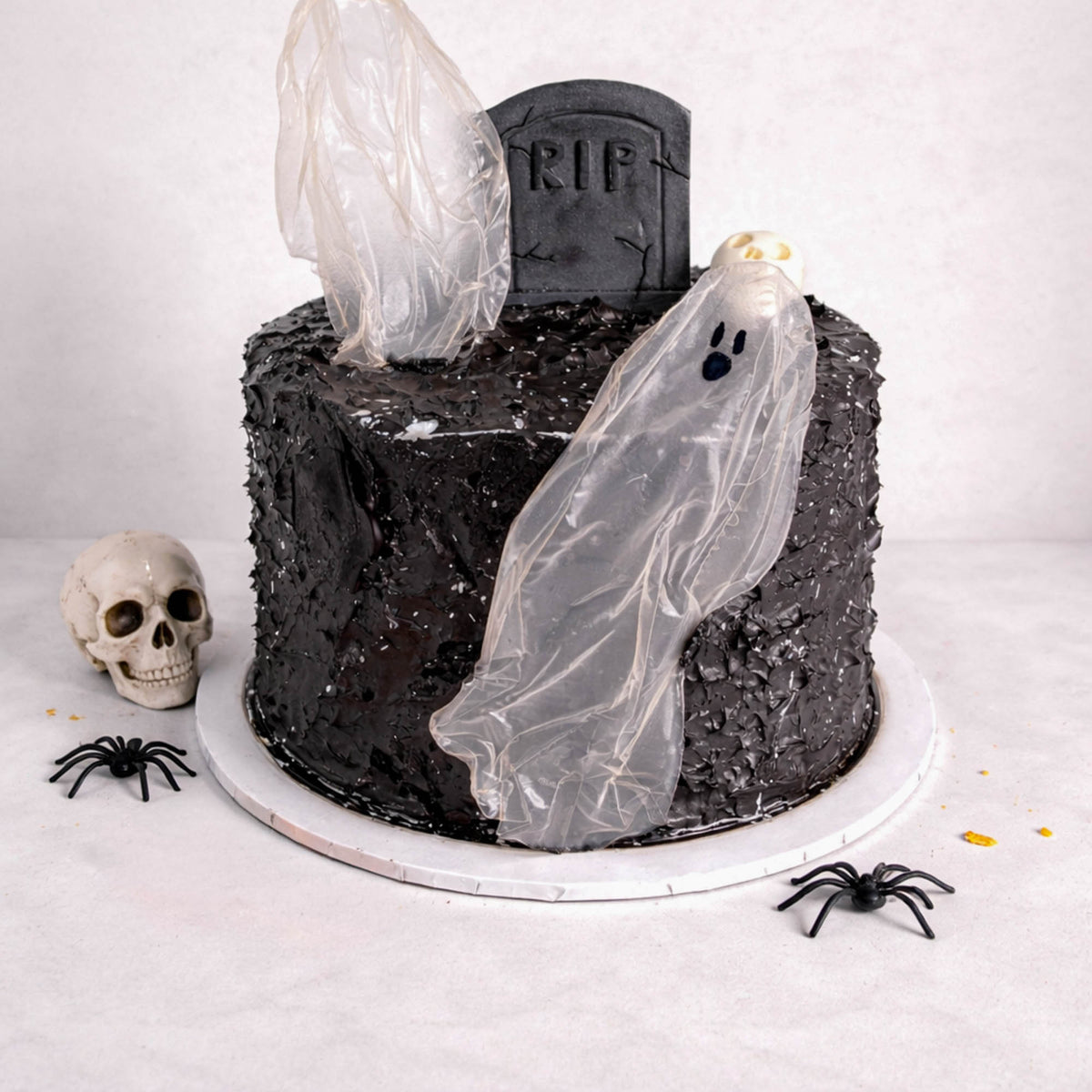 Tombstone Cake with black buttercream, ghost figures, a fondant tombstone, skulls and spiders
