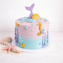 Mermaid Cake with ombre buttercream, a purple mermaid tail, gold shell and edible sand