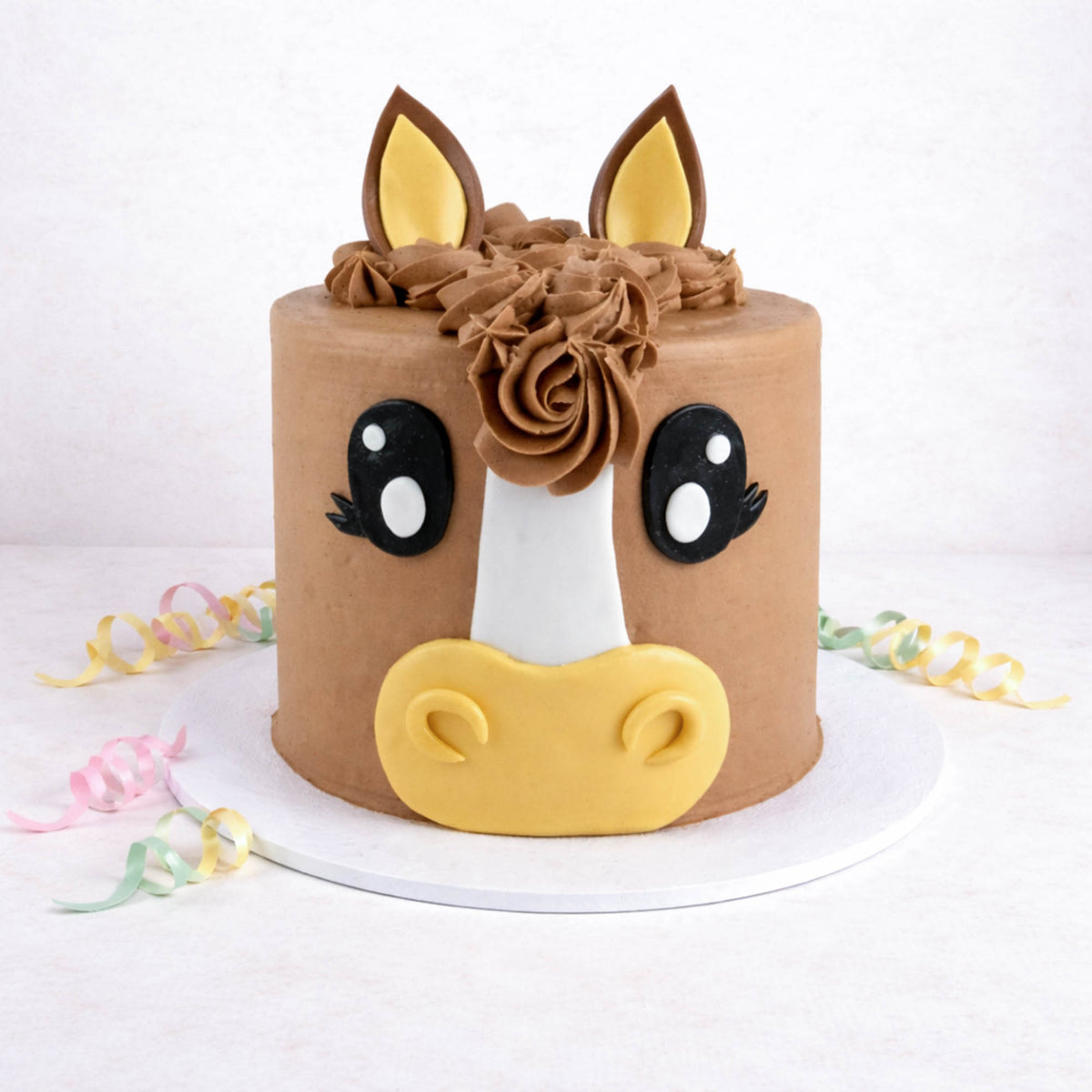 Free From Horse Cake with chocolate buttercream, a fondant face and rosette mane, with pastel ribbons