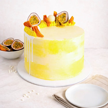 Gluten friendly Free From White Chocolate Passionfruit Cake with swirls, passionfruit, dried mango and a white chocolate ball