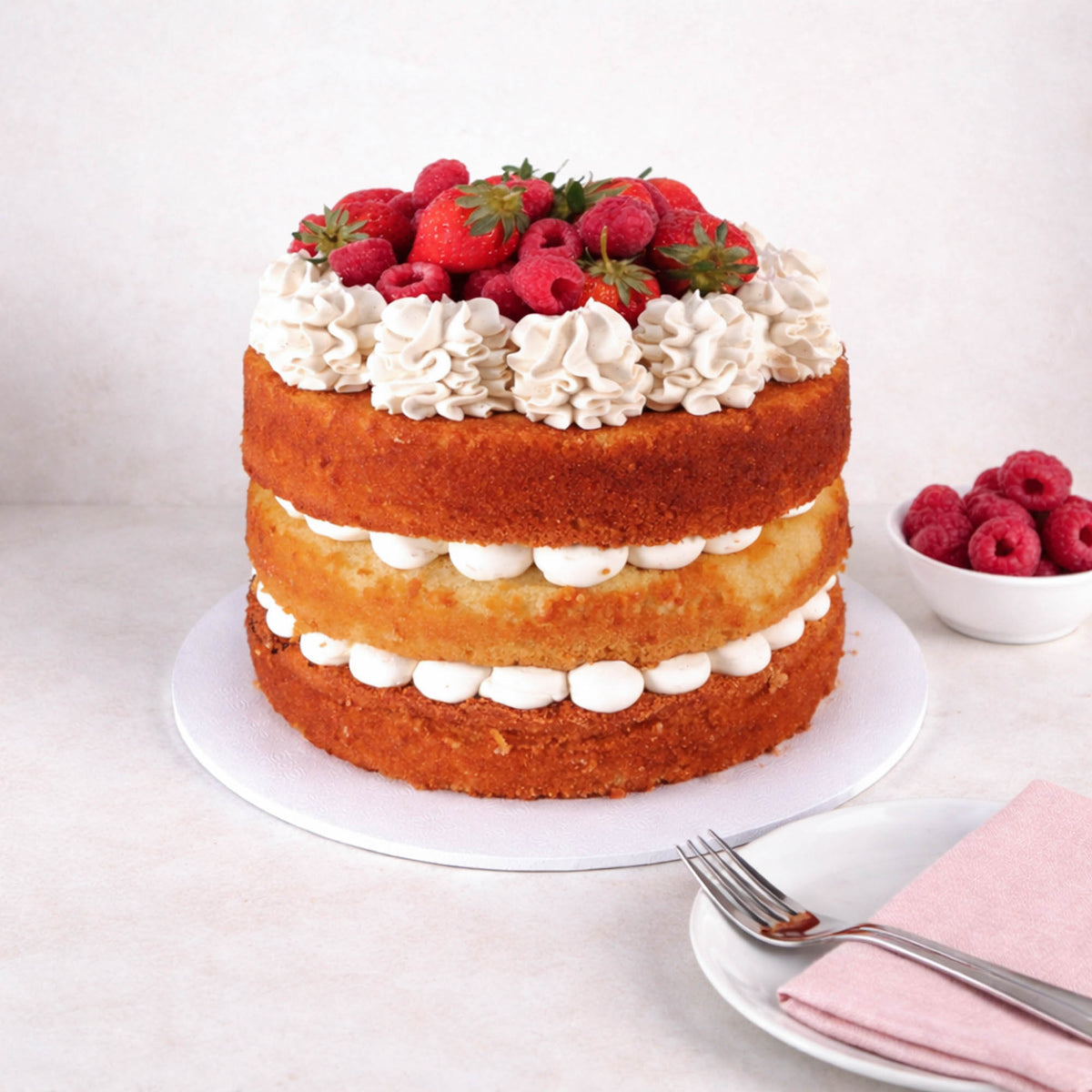 Victoria Sponge Cake with three layers of sponge, buttercream and jam, topped with strawberries and raspberries