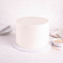 Undecorated Cake with smooth white buttercream, next to a bowl of sprinkles
