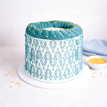 Free From Stencil Cake with a teal leaf pattern, rosettes and yellow sugar pearls