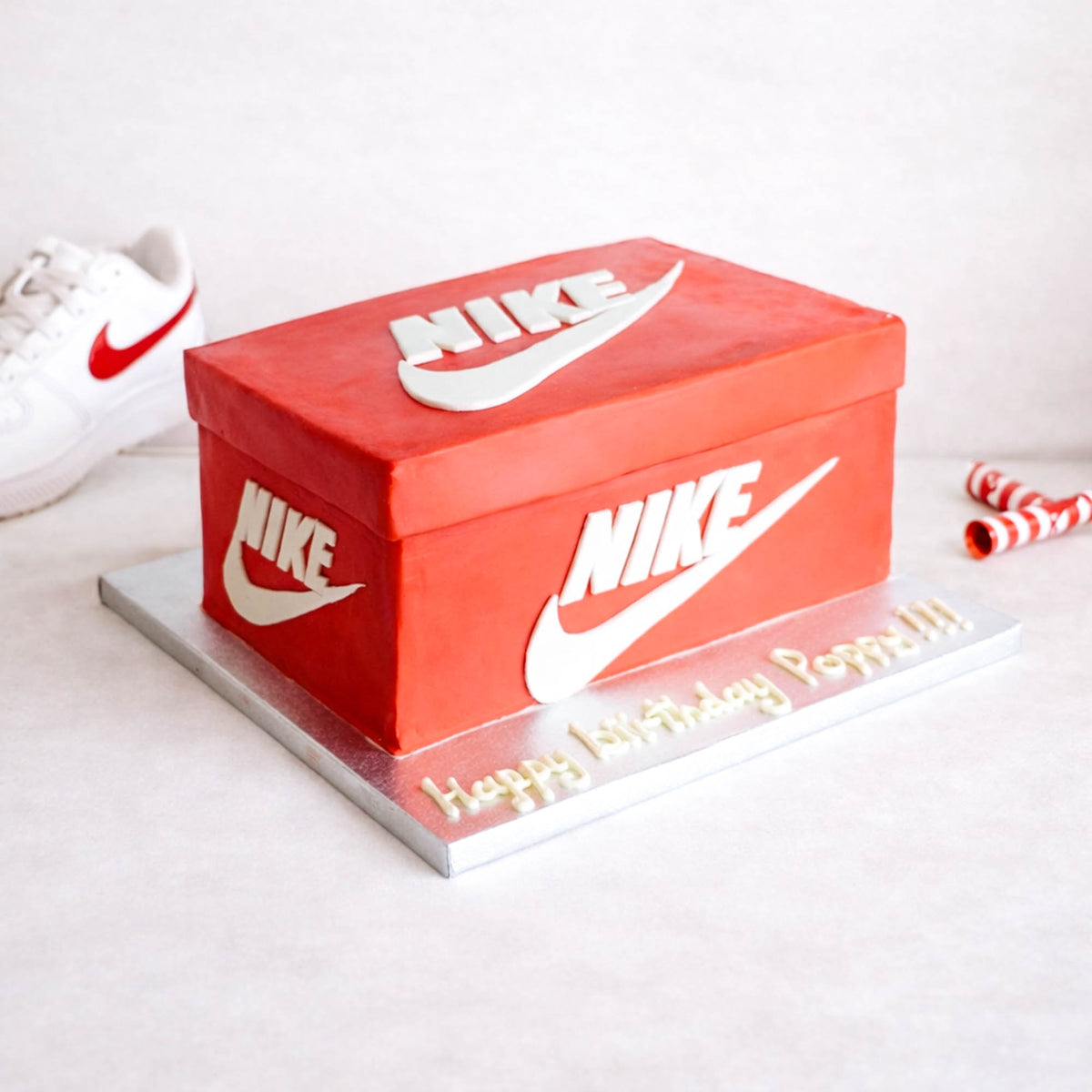 Shoe Box Cake made to look like a red trainer box, with a birthday message on a silver board
