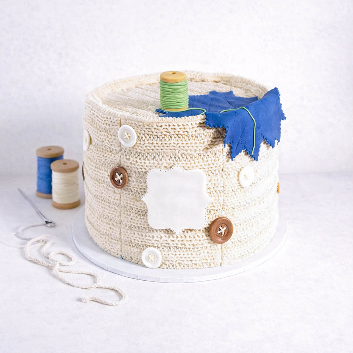 Needlecraft Cake made to look like a knitting basket, with edible buttons, a cotton reel and fabric