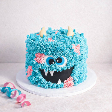 Monster Cake with piped buttercream fur, fondant horns and googly eyes, with party streamers