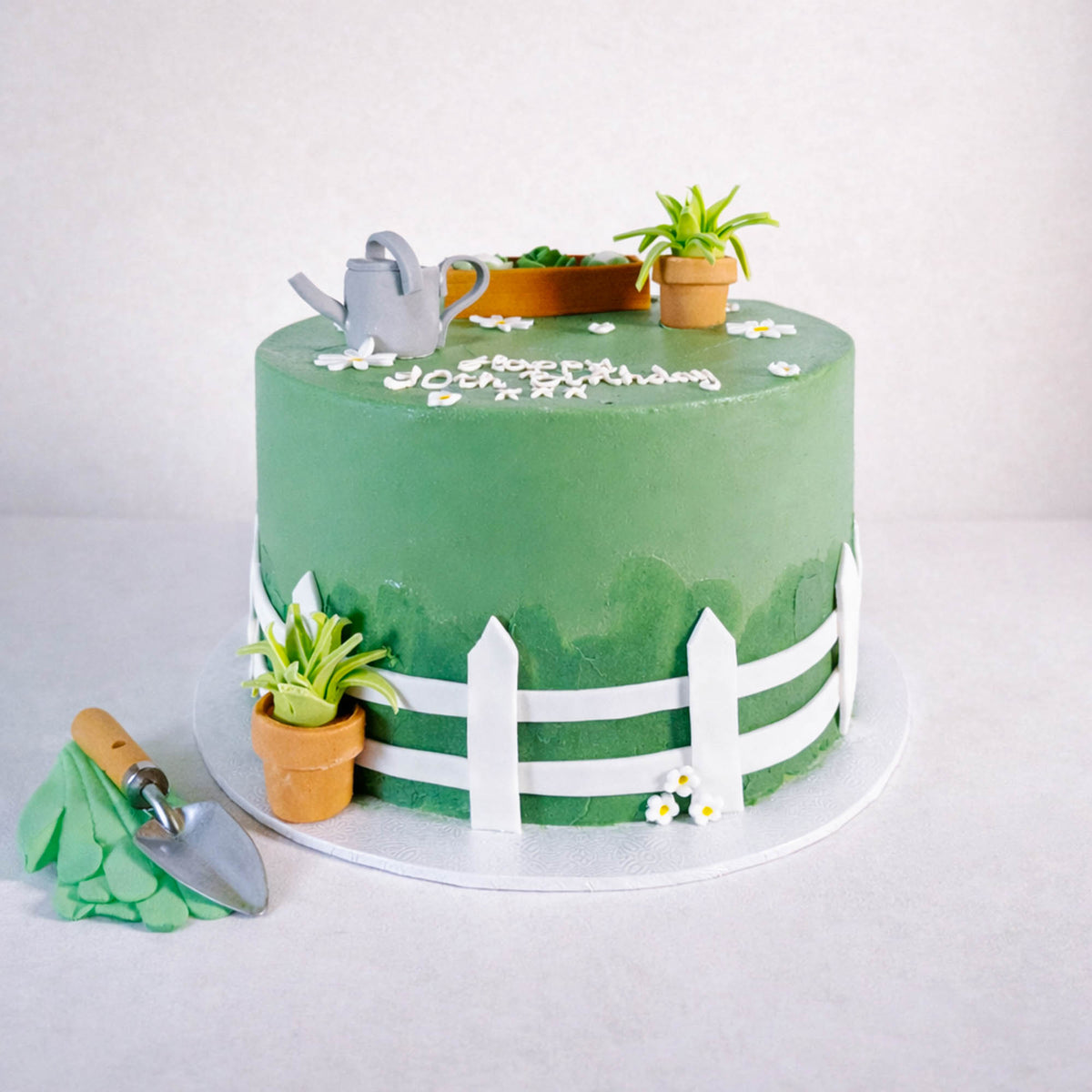Free From Gardening Cake with a fondant picket fence, garden decorations and a happy birthday message