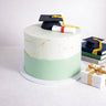 Graduation Cake with two tone buttercream, a fondant mortarboard and scroll, next to a gift and books