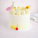 8 inch Cocktail Cake with white buttercream, rosettes, pineapple, cherries, paper straws and a cocktail umbrella
