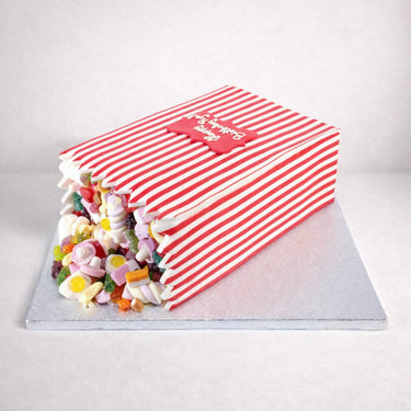 Sweety Box Cake made to look like a tipped over sweet bag, with colourful sweets spilling out