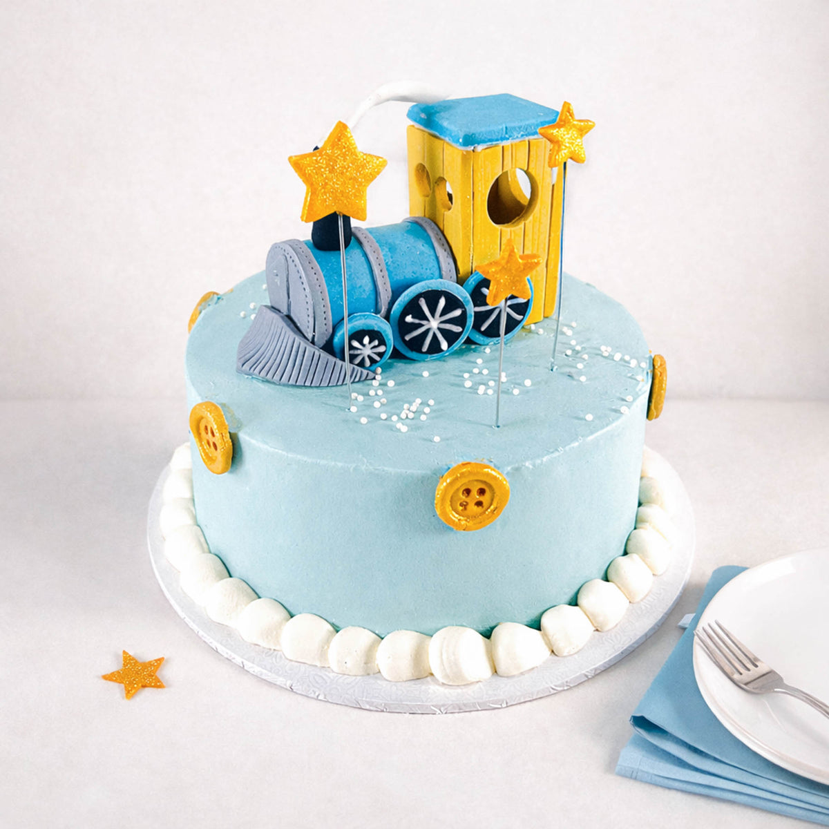 Mini Train Cake with a blue fondant train, gold stars, piped dots and yellow buttons