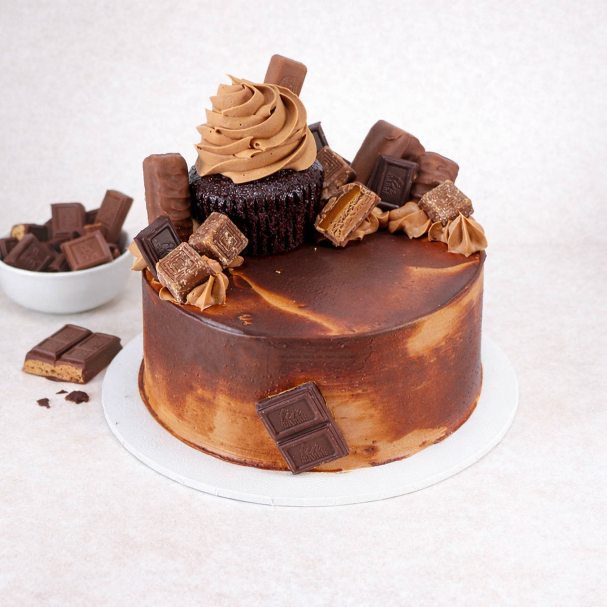 Mini Chocolate Overload Cake topped with a chocolate cupcake, broken chocolate bars and sweets