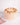 Mini Carrot Cake with pale-peach buttercream, topped with cream rosettes, honeycomb bits, and edible petals, beside a pink napkin and silver fork.