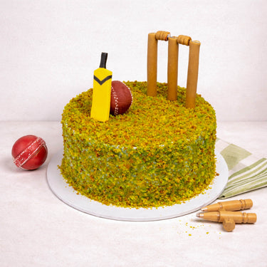 Mini Cricket Cake with green crumb grass, a bat, ball and stumps