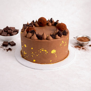 Mini Triple Chocolate Cake with chocolate buttercream, truffles and biscuit pieces, next to chocolate chunks