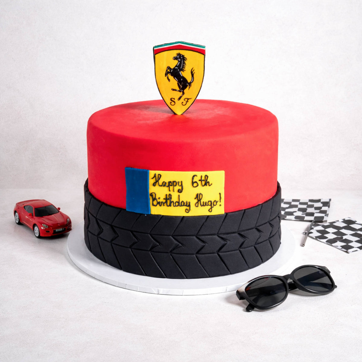 Free From two tier red Car Cake with a tyre tread design, racing shield and a birthday message, with a toy car