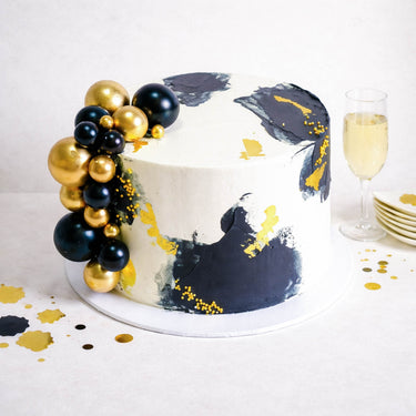 Free From Gold Abstract Cake with dark buttercream, gold flecks and decorative balls, with champagne