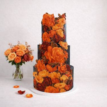 Floral Cutout Wedding Cake in black with orange sugar flowers, next to a vase of roses