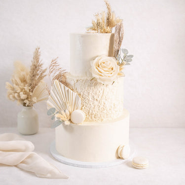 Boho Wedding Cake with dried grasses, pampas, palm leaves, a cream rose, eucalyptus and white macarons