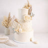 Boho Wedding Cake with dried grasses, pampas, palm leaves, a cream rose, eucalyptus and white macarons