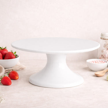 White ceramic cake stand with a cake, strawberries and sweets