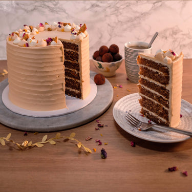 Four layer Carrot Cake with buttercream and edible petals, with a slice on a plate