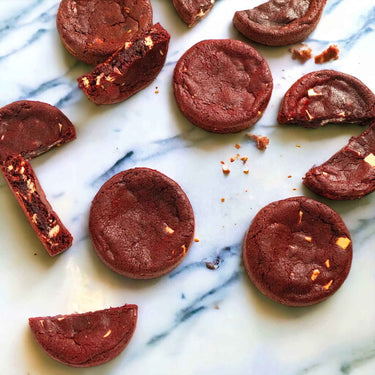 Red Velvet Cookies with white chocolate chips, whole and broken, on a stone slab