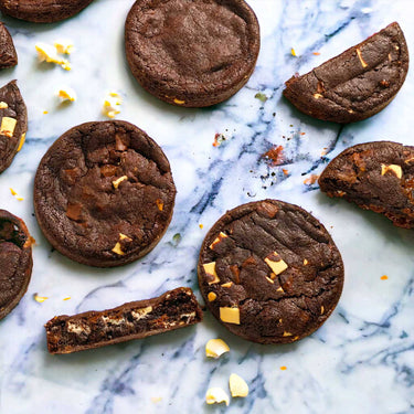 Triple Chocolate Cookies with white and milk chocolate chunks, whole and broken, on marble