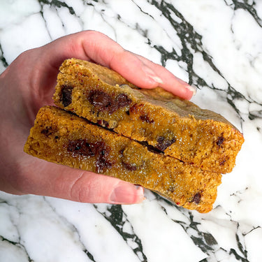 Hand holding two Chocolate Chip Cookies with melted chocolate chips