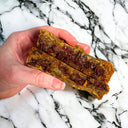 Hand holding a gooey cookie broken open to show melted chocolate