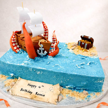 Pirate ship birthday cake with an octopus and treasure chest on a blue sea