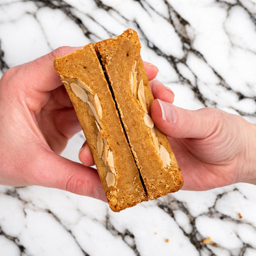 Hands holding a thick Almond Croissant Cookie topped with flaked almonds